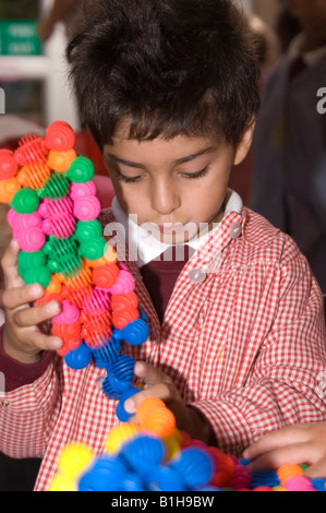 Giovani schoolboy giocare con un giocattolo di costruzione Foto Stock