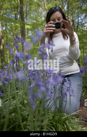 Giovane donna di scattare una foto delle Bluebells Foto Stock