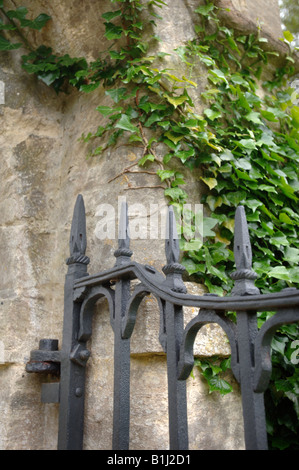 Un coperto di edera COTSWOLD GATEPOST IN PIETRA CON cancellata in ferro battuto REGNO UNITO Foto Stock