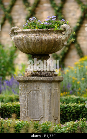 Un antico urna di pietra in un giardino murato con IVY addestrato in un reticolo DESIGN UK Foto Stock