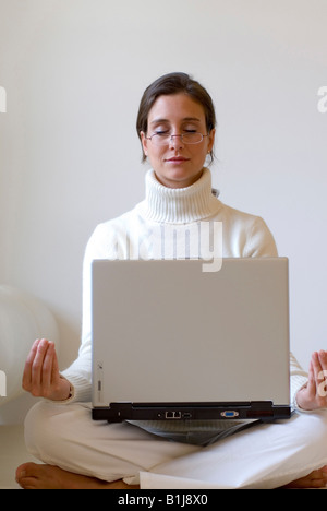 Giovane donna pratica dello yoga con un notebook sul suo giro Foto Stock