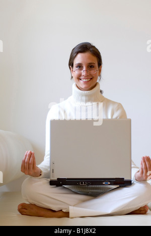 Giovane donna pratica dello yoga con un notebook sul suo giro Foto Stock