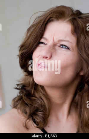 Giovane bella donna con ricci capelli castani, gurning Foto Stock