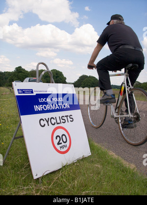 Ciclista e 20 mph segnale di limite di velocità nel Parco di Richmond, Surrey. Regno Unito Foto Stock