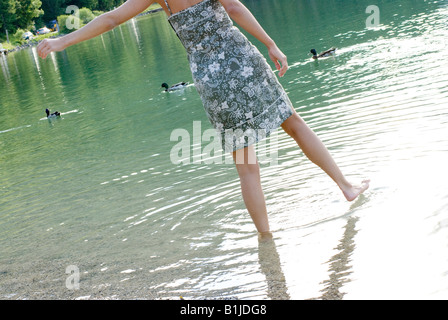 Giovane donna con abiti estivi guadare in un mare Foto Stock