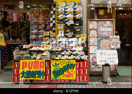 Un display di formatori al di fuori di un negozio di calzature nel centro di Kyoto, Giappone, offrendo sconti sui marchi leader Foto Stock