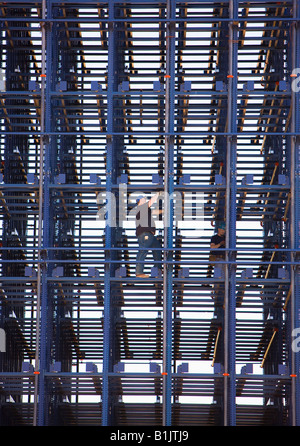 Un lavoratore di acciaio si arrampica lungo le travi in acciaio in un cantiere. Foto Stock