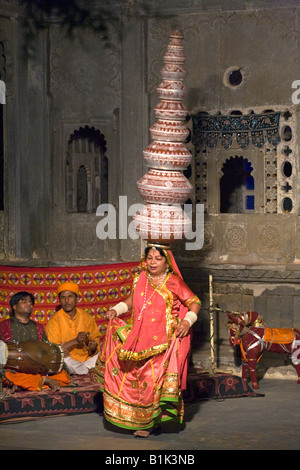 Una donna di Rajasthani esecuzione di danza tradizionale di trasportare nove brocche d'acqua sulla sua testa BAGORE KI HAVELI in Udaipur Rajasthan in India Foto Stock