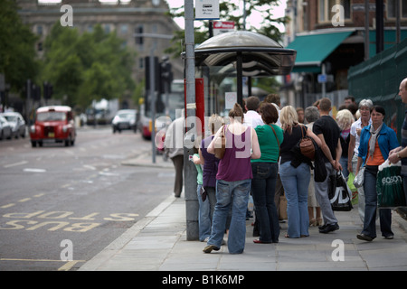 La gente in coda ad una fermata del bus durante il sabato shopping belfast Irlanda del Nord Foto Stock