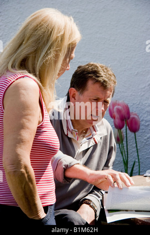 Uomo maturo e la donna discutendo il contenuto di documenti cartacei su un tavolo di fronte a loro Foto Stock