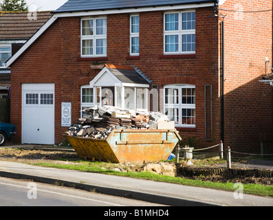 Un suburban casa unifamiliare sottoposti a riparazioni, lavori di ristrutturazione. Builder saltare. Hampshire. Regno Unito. Foto Stock