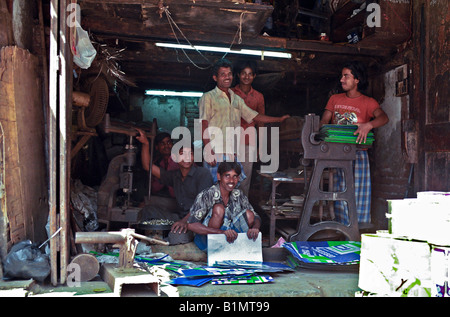 INDIA MUMBAI MAHARASHTRA dei lavoratori in un negozio di fabbricazione di metalli presentano orgogliosamente come hanno tagliato fino lattine metalliche e indicazioni per il riciclaggio Foto Stock