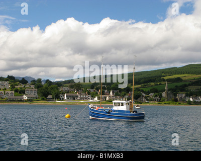 Blue barca da pesca per il suo colore giallo boa di ormeggio off Lamlash, Isle of Arran, Scozia. Visto da seaward. La Chiesa di San Giorgio si vede sulla destra Foto Stock