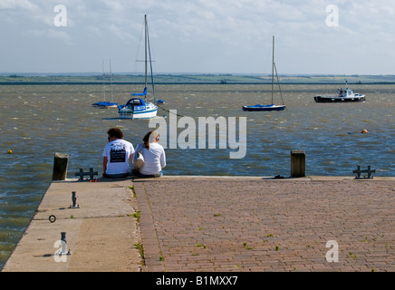 Un uomo e una donna seduta sul bordo della banchina a Leigh on Sea in Essex. Foto Stock