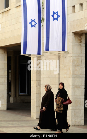 Due donne palestinesi camminare sotto bandiere israeliane nei pressi del palazzo comunale in Gerusalemme. Foto Stock