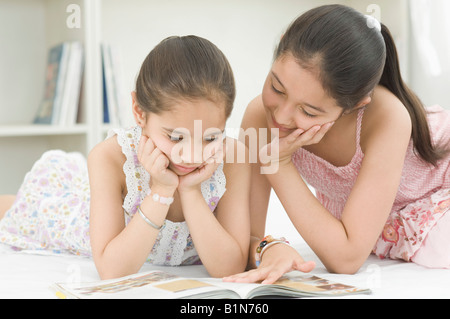Close-up di due ragazze giacente sul letto e la lettura di un libro Foto Stock