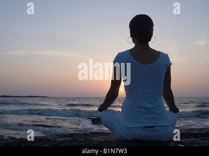 Vista posteriore di una giovane donna a praticare yoga sulla spiaggia, Mud Island, Mumbai, Maharashtra, India Foto Stock