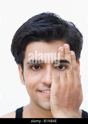 Ritratto di un giovane uomo che copre il suo unico occhio con la mano Foto Stock