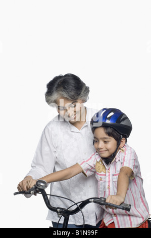 Donna matura contribuendo a suo nipote di cavalcare una bicicletta Foto Stock