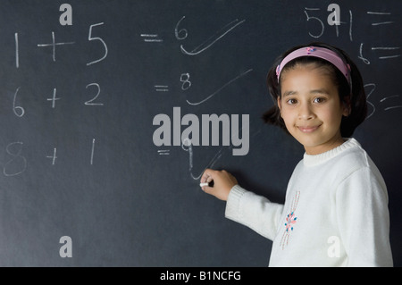 Ritratto di una ragazza di risolvere i simboli matematici su una lavagna Foto Stock