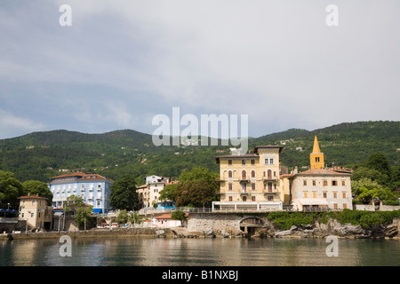 Vista offshore di antica città fortificata edifici su Kvarner Gulf Coast sotto il monte Ucka mountain. Lovran Istria Croazia Europa Foto Stock