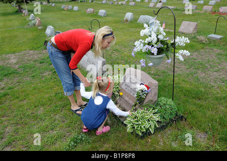 Madre e figlia luoghi fiori sul luogo di sepoltura Foto Stock