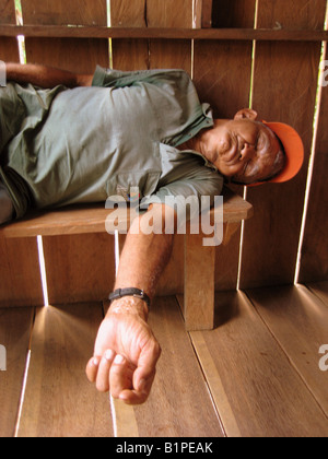 Il vecchio uomo brasiliano di dormire sul banco in casa Foto Stock