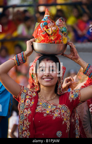 Una donna di Rajasthani porta effigi di Shiva e Parvati presso il festival di GANGUR o MEWAR FESTIVAL in Udaipur Rajasthan in India Foto Stock