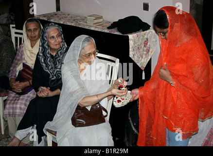 Donna musulmana distribuisce fiori presso una casa in occasione di Moulid al Nabi profeti ( PBSL ) compleanno , India Foto Stock