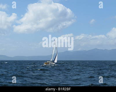 Yacht a vela con una brezza fresca nel Firth of Clyde, Scozia. L'isola di Arran a distanza Foto Stock