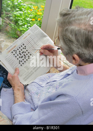 Donna anziana facendo un cruciverba usando il suo cervello per mantenerlo attivo Foto Stock