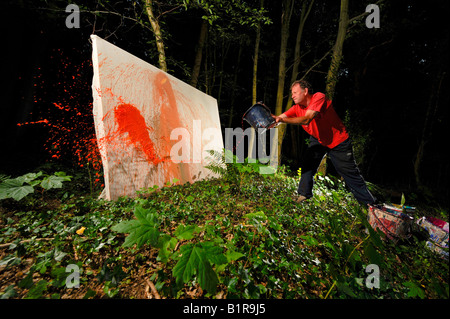 Sussex artista e illustratore David Armitage utilizzando una vernice gettati dalle benne per creare una grande tela astratta. Foto Jim Holden. Foto Stock