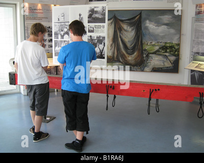 I giovani visitatori guardando le foto correlate di successo i tentativi di fuga dalla Germania Est presso il privato Checkpoint Charlie Berlino Germania Foto Stock