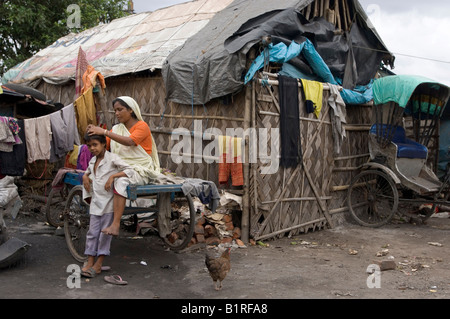 Madre guardando attraverso suo figlio di capelli, la ricerca per i pidocchi nella baraccopoli di quella di Howrah, Hooghly, West Bengal, India Foto Stock