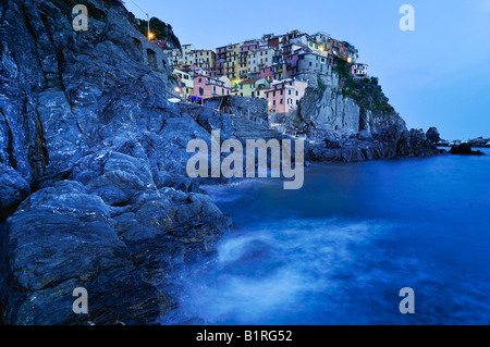 Villaggio di Manarola arroccata su coste scoscese al crepuscolo, la Liguria Cinque Terre, Italia, Europa Foto Stock