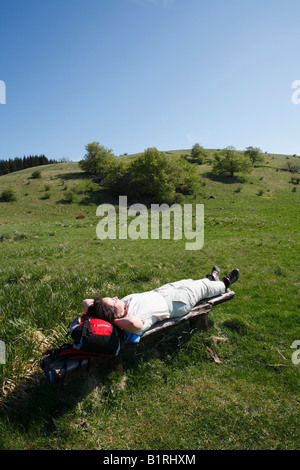 Donna sdraiata su un vecchio banco di legno sul Monte Himmeldunkberg, Rhoen montagne, bassa Franconia, Baviera, Germania, Europa Foto Stock