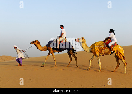 Un beduino cammelli leader con i turisti in un tour nel deserto di Abu Dhabi, Emirati Arabi Uniti, Asia Foto Stock