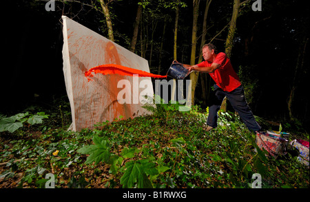 Sussex artista e illustratore David Armitage utilizzando una vernice gettati dalle benne per creare una grande tela astratta. Foto Jim Holden. Foto Stock