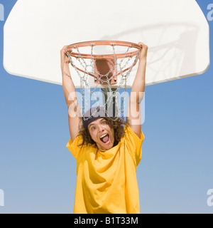 Un teenager di giocatore di basket pende dal cerchio Foto Stock