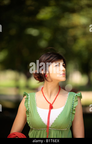 Signora giovane all'aperto osservando la natura intorno a lei con una faccia pacifica Foto Stock