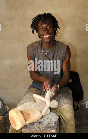 Sorridente giovani scultori in legno con Rasta guardare la lucidatura di una scultura in legno presso il centro sculture in Aburi, Regione orientale, Ghana Foto Stock