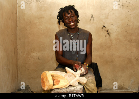 Sorridente giovani scultori in legno con Rasta guardare la lucidatura di una scultura in legno presso il centro sculture in Aburi, Regione orientale, Ghana Foto Stock