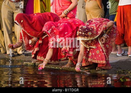 Rajasthani donne lavare i petali di rose sulla riva del lago Pichola per il festival di GANGAUR UDAIPUR RAJASTHAN IN INDIA Foto Stock