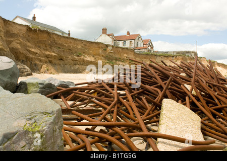 Case sul bordo scogliera e rimane vecchio le difese del mare dopo grave erosione costiera Happisburgh Costa North Norfolk REGNO UNITO Foto Stock