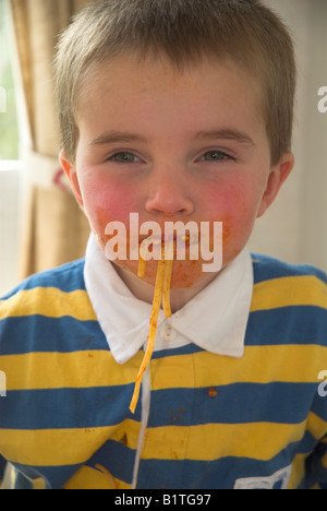 Ragazzo di salire in un pasticcio di mangiare spaghetti alla bolognese Foto Stock