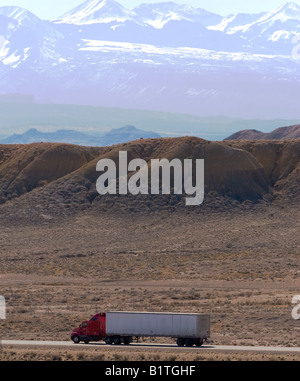 Un generico rimorchio bianco viene tirato giù dalla strada in tutta l'alta terreno desertico di Eastern Utah. Foto Stock