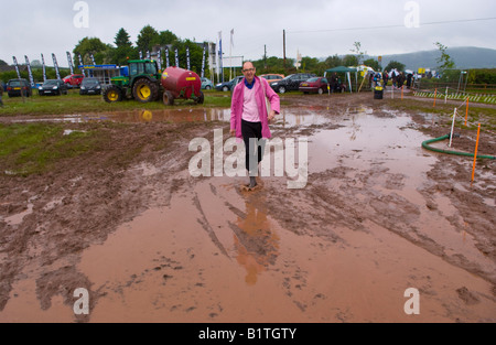 Robin Wight in cappotto rosa attraversando allagato parcheggio presso il Guardian Hay Festival 2008 Hay on Wye Powys Wales UK UE Foto Stock