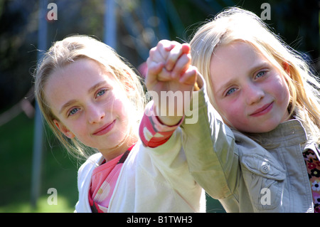 Fotografia delle due sorelle fiducioso giocare felicemente nel loro giardino e sorridente alla fotocamera. Foto Stock