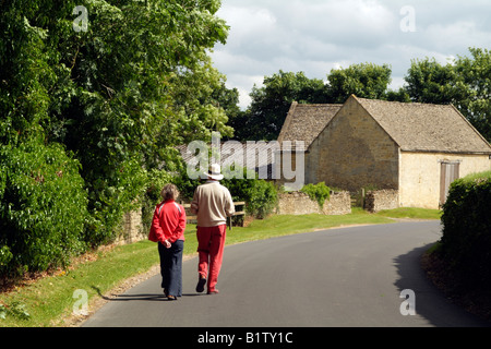 Giovane a piedi attraverso Guiting Power village Cotswolds Gloucestershire in Inghilterra Foto Stock