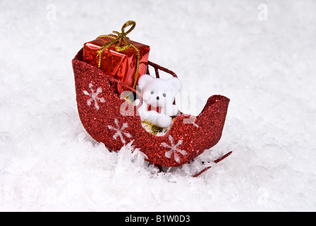 Un orsacchiotto bianco si siede in un rosso sleigh in attesa di santa Foto Stock